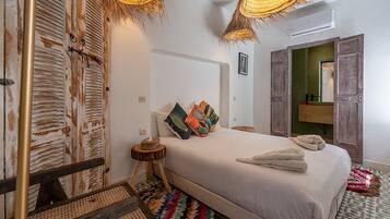 Un dormitorio con cama, mesita de noche, espejo y puerta.