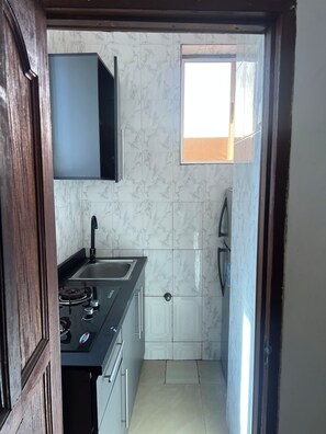 A compact kitchen with a gas stove, sink, and a window. - New Listing (Accra)