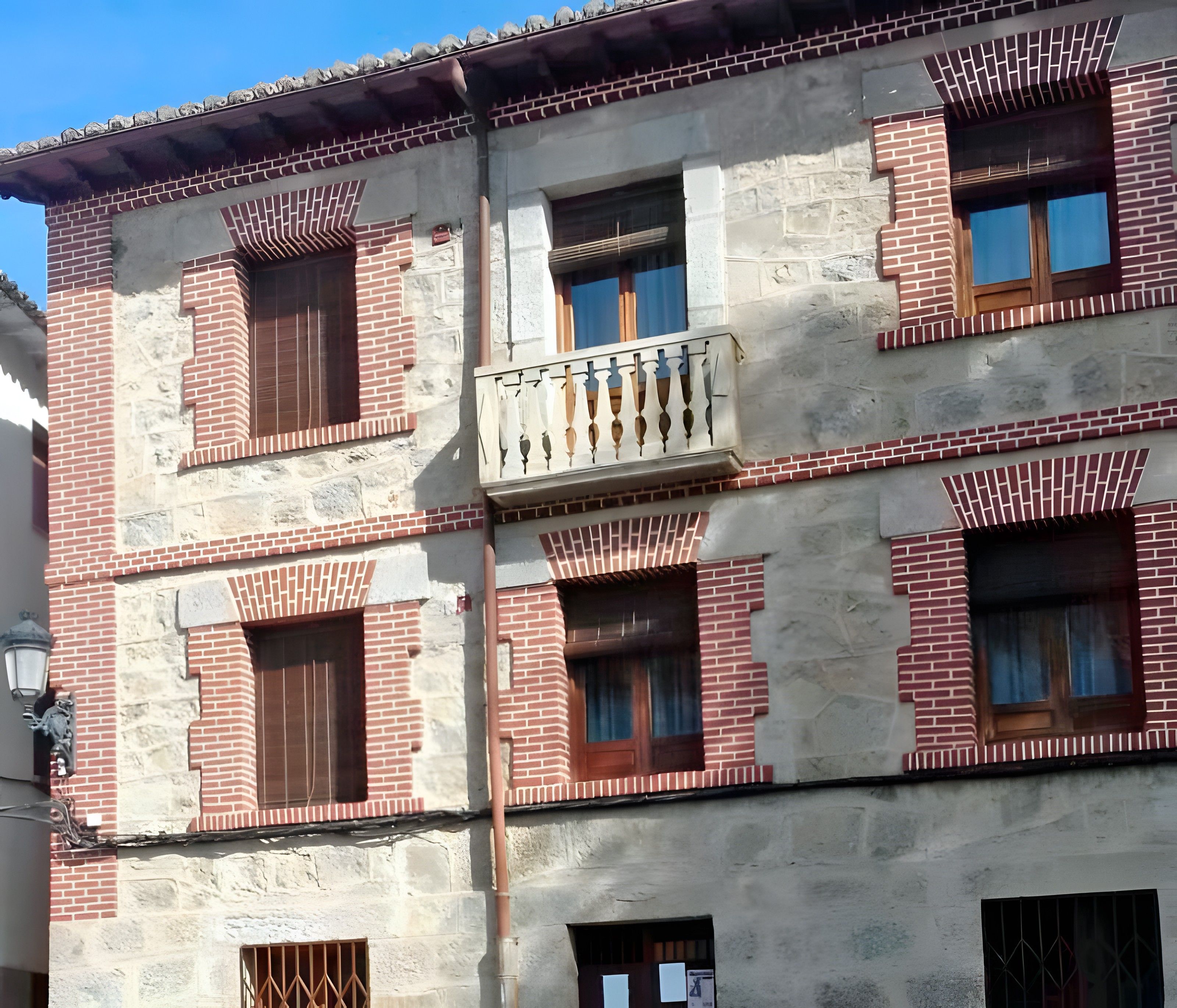 Un edificio de varios pisos con fachadas de ladrillo, múltiples ventanas y un balcón.