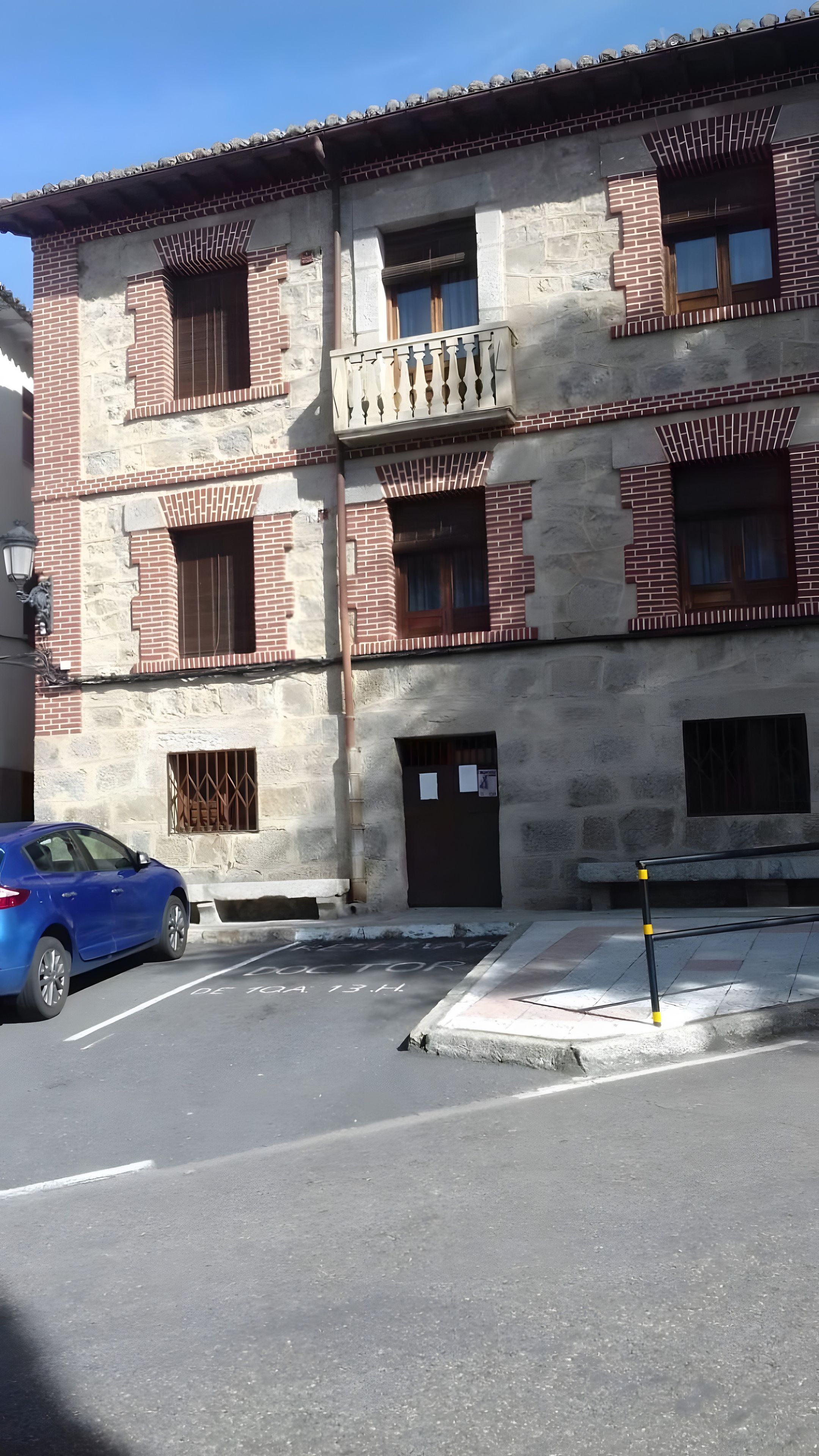 Un edificio de varios pisos con fachada de ladrillo, varias ventanas y una entrada visible.