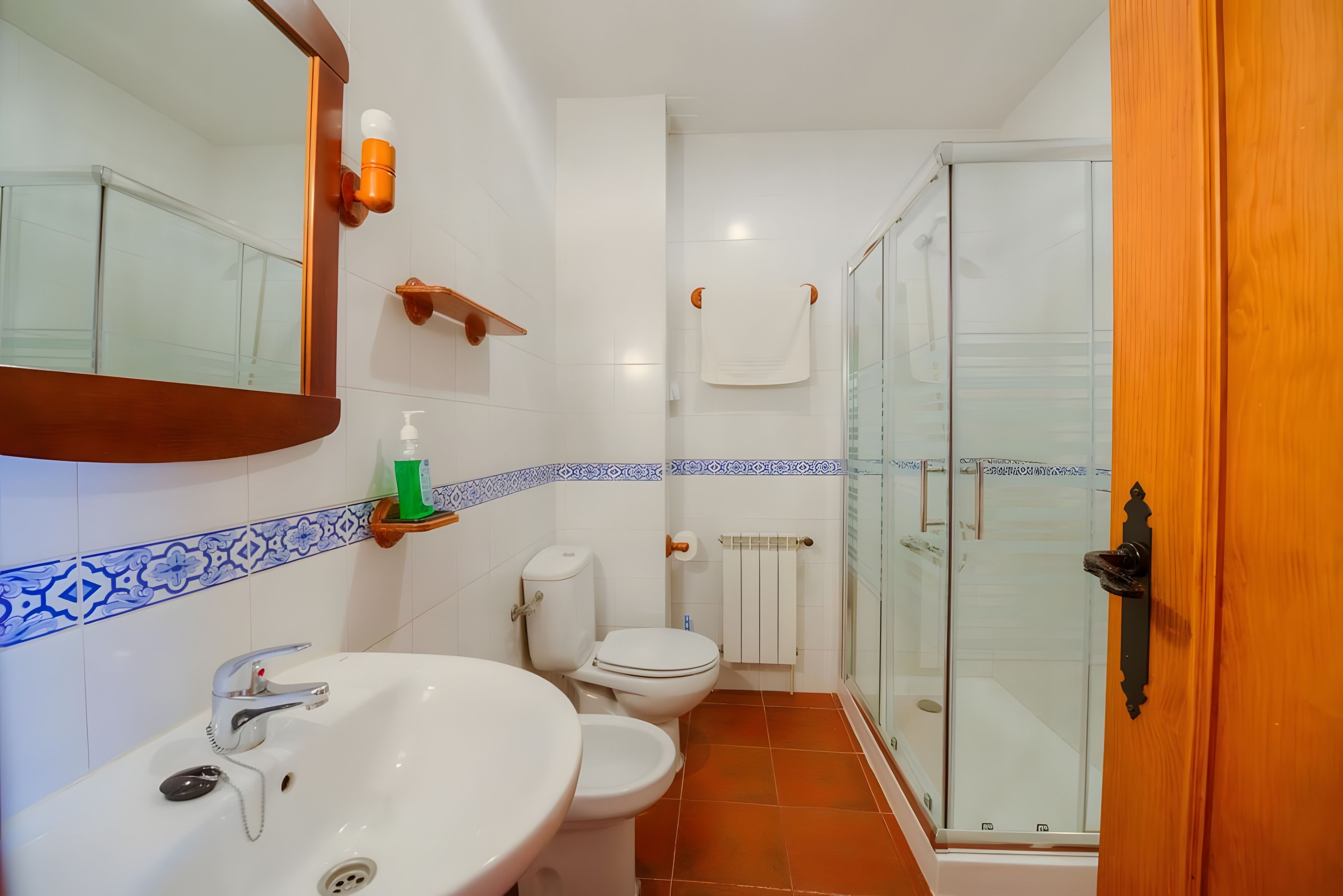 A bathroom with a sink, toilet, and a glass-enclosed shower area.
