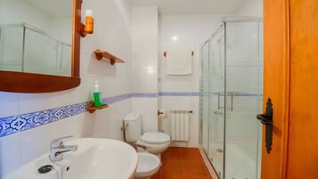 A bathroom with a sink, toilet, and a glass-enclosed shower area.