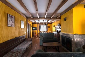 A room with wooden beams, a fireplace, a sofa, and a television. - Country House 'La Casa Grande' with Fireplace, Patio with Barbecue and Wi-Fi (El Barco de Ávila)