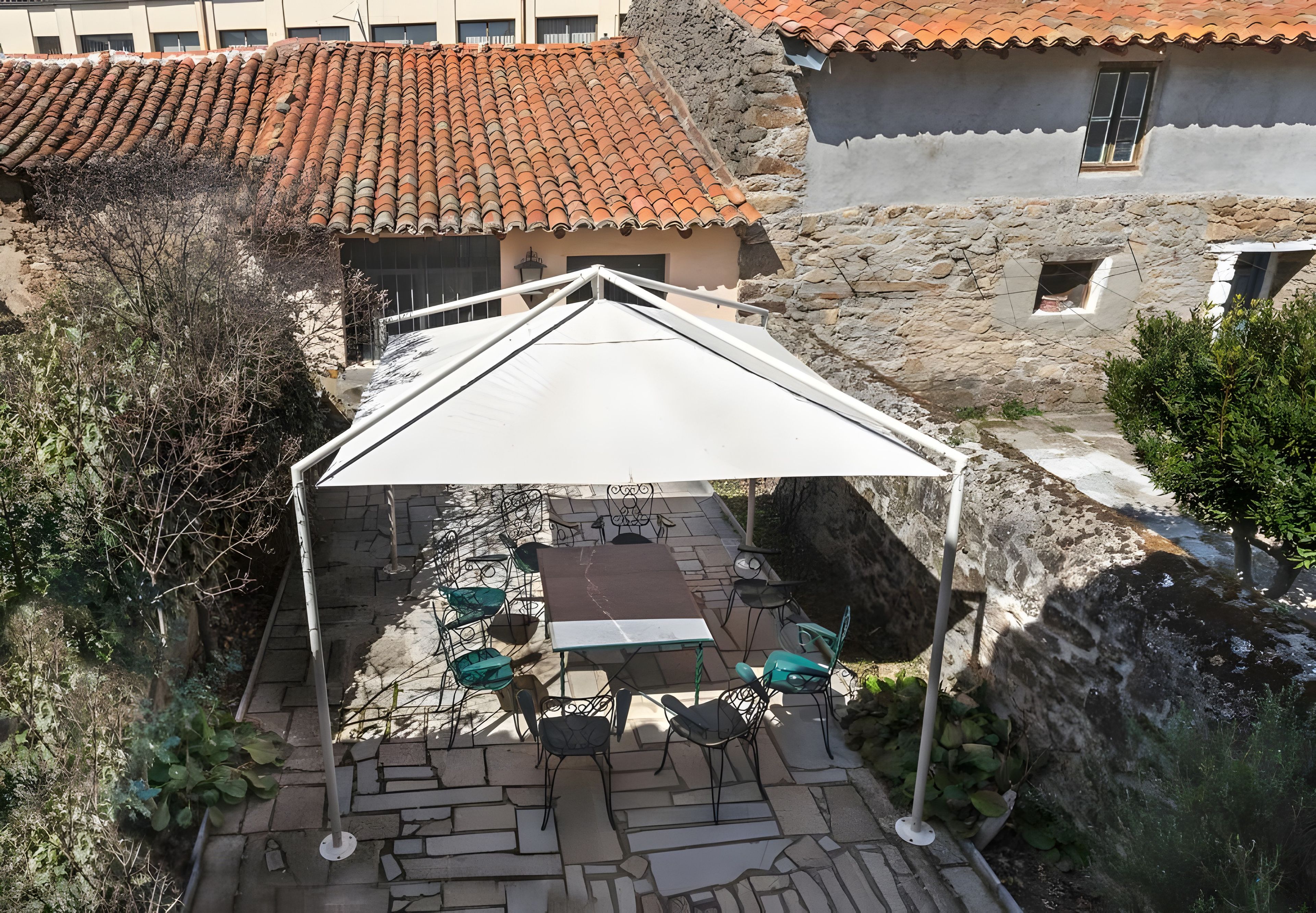 A covered outdoor seating area with stone flooring and metal chairs.