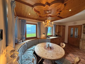 A cozy room with a wooden ceiling, a round table, a bench, and a view of the outdoors. - New Listing (Kirchberg in Tirol)