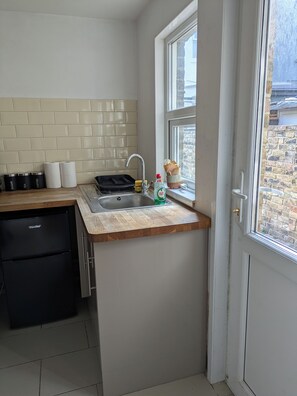 A kitchen with a sink, a refrigerator, and a window with a view of a brick building. - Quiet 2 bed house in Ramsgate. (Ramsgate)