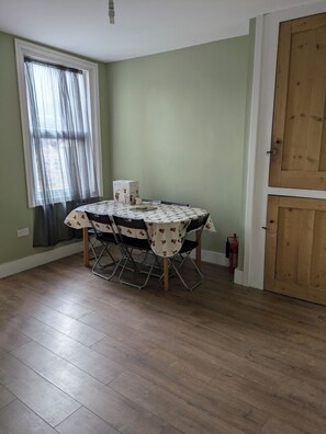 A dining area with a round table, chairs, and a fire extinguisher. - Quiet 2 bed house in Ramsgate. (Ramsgate)