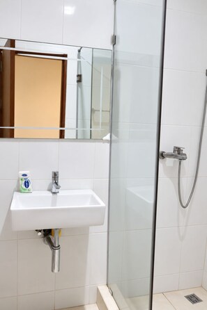 A bathroom with a glass-enclosed shower, a white sink, and a mirror above the sink. - Central 3BR Escape behind West Hills Mall (Mile 11)