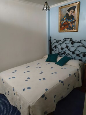 A bed with a patterned bedspread, a decorative headboard, and a painting above it. - Country House 'Casa Rural El Zapatero De Sexifirmo' with Balcony (Piedrahíta)