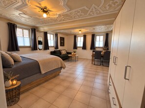 A hotel room with a bed, a sofa, a dining table with chairs, and a large wardrobe. - Historic Studio for up to 4 people (Ochsenfurt)