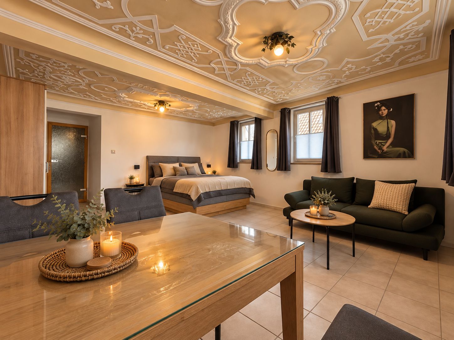 A modern bedroom with a large bed, a sofa, a dining table with candles, and a decorative ceiling.