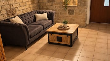 A living room with a stone wall, a dark sofa, a wooden coffee table, and a door.