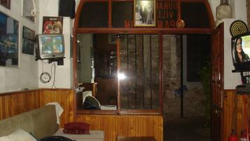 Una habitación con un banco de madera, un televisor y un cuadro colgado en la pared.
