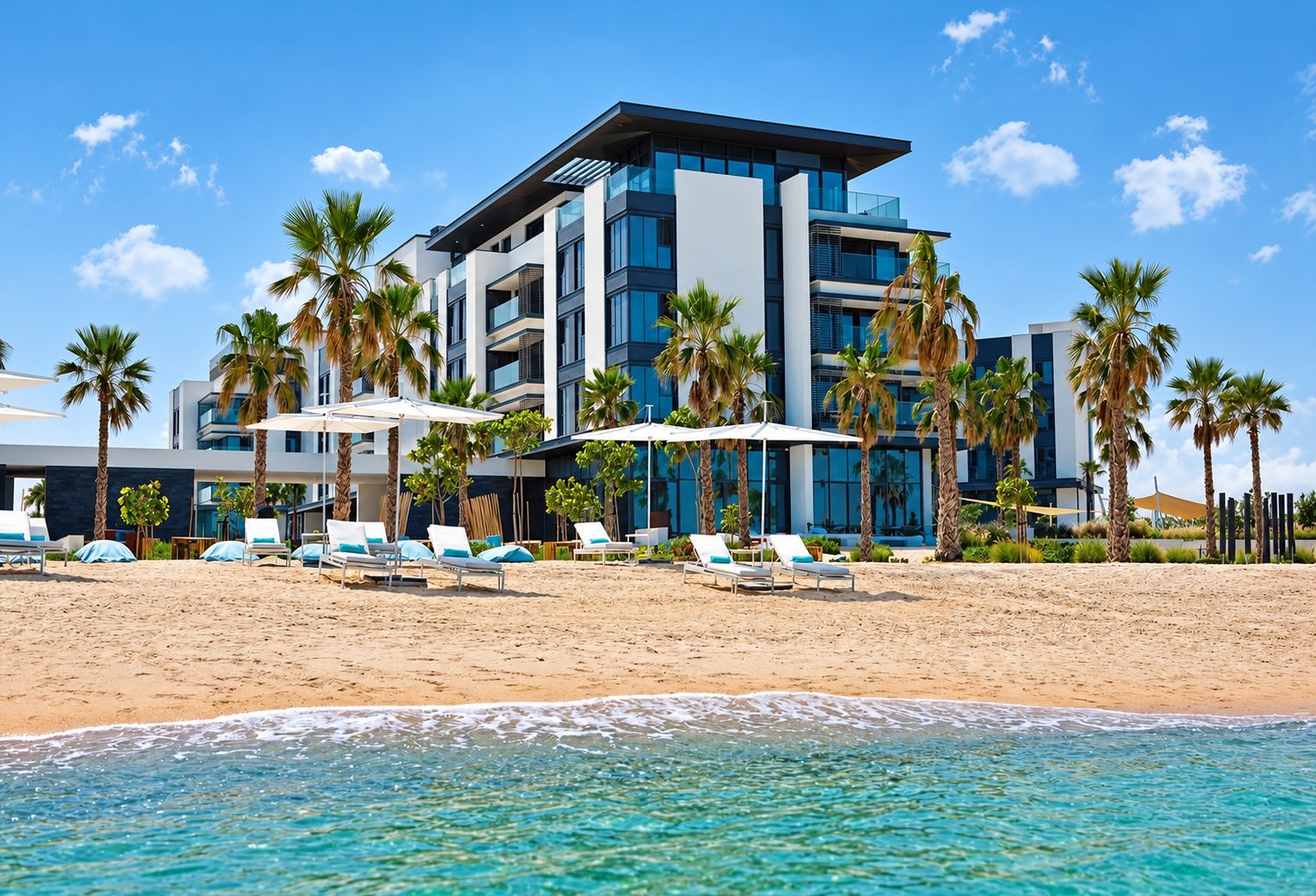 A modern hotel with a poolside area, palm trees, and beach chairs.
