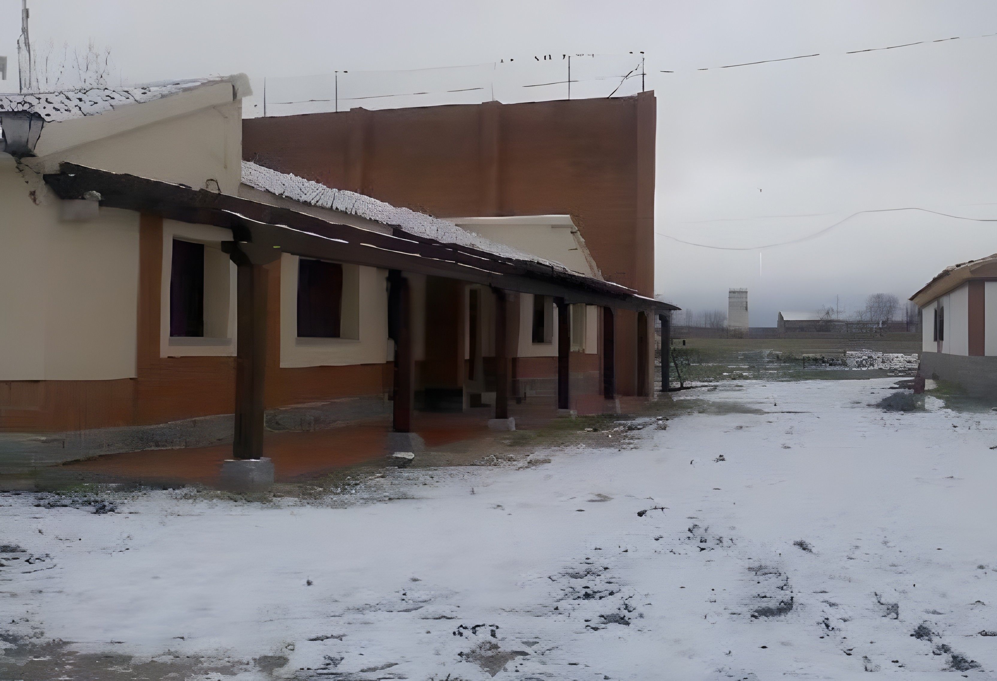 Un edificio con una zona exterior techada y suelo cubierto de nieve.