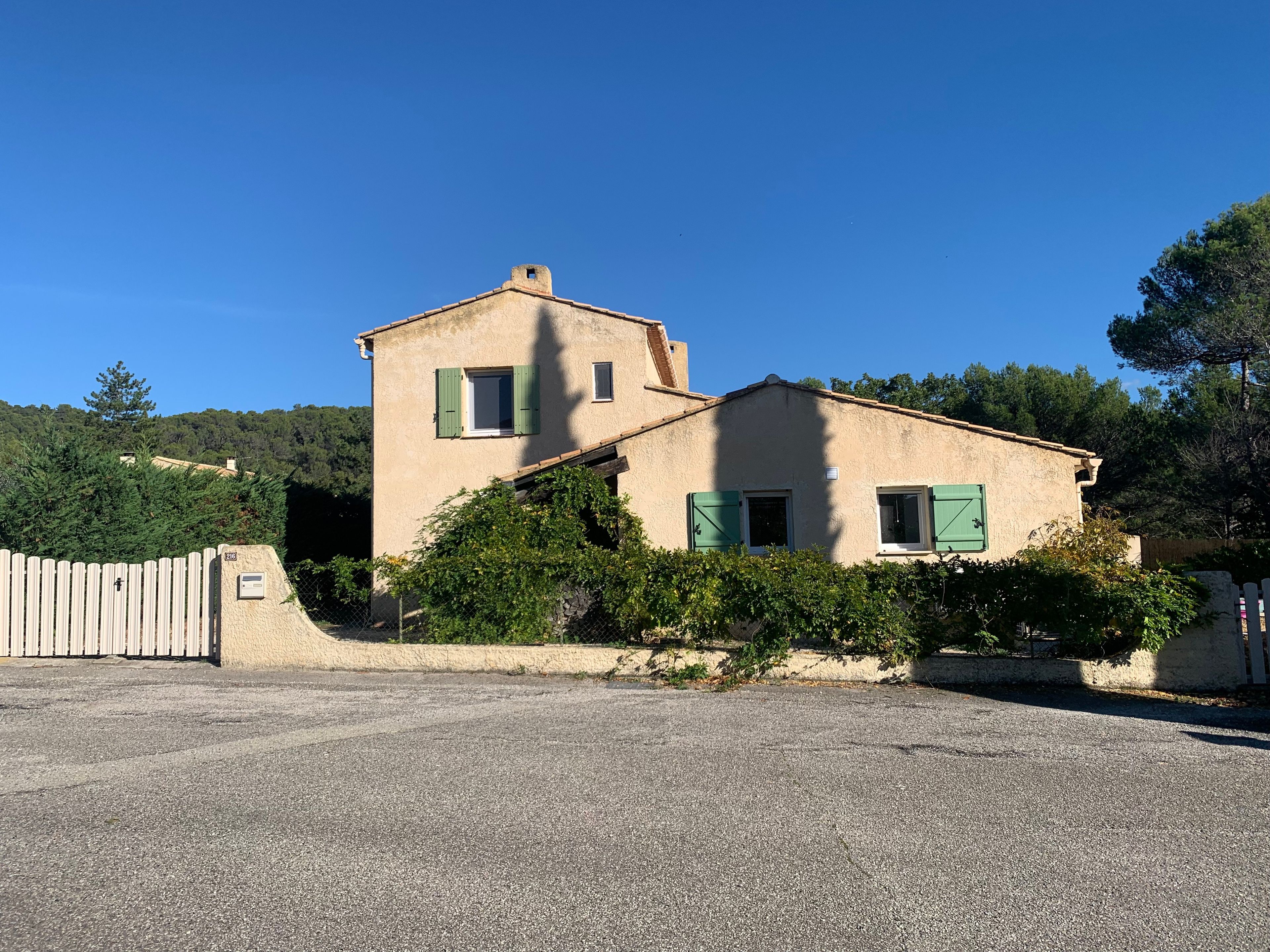 Un bâtiment à deux étages avec une allée en gravier et une clôture en bois.