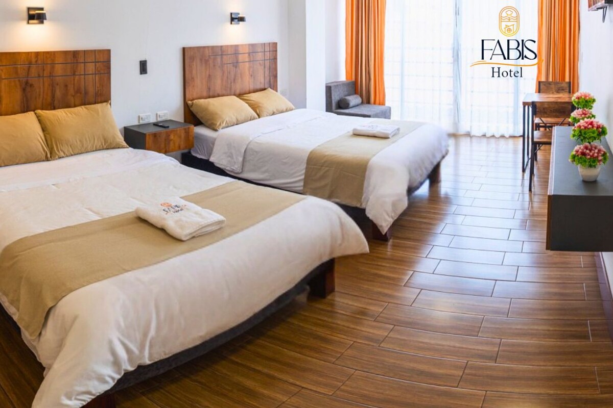 Habitación de hotel con dos camas, cabeceros de madera y suelo de madera.