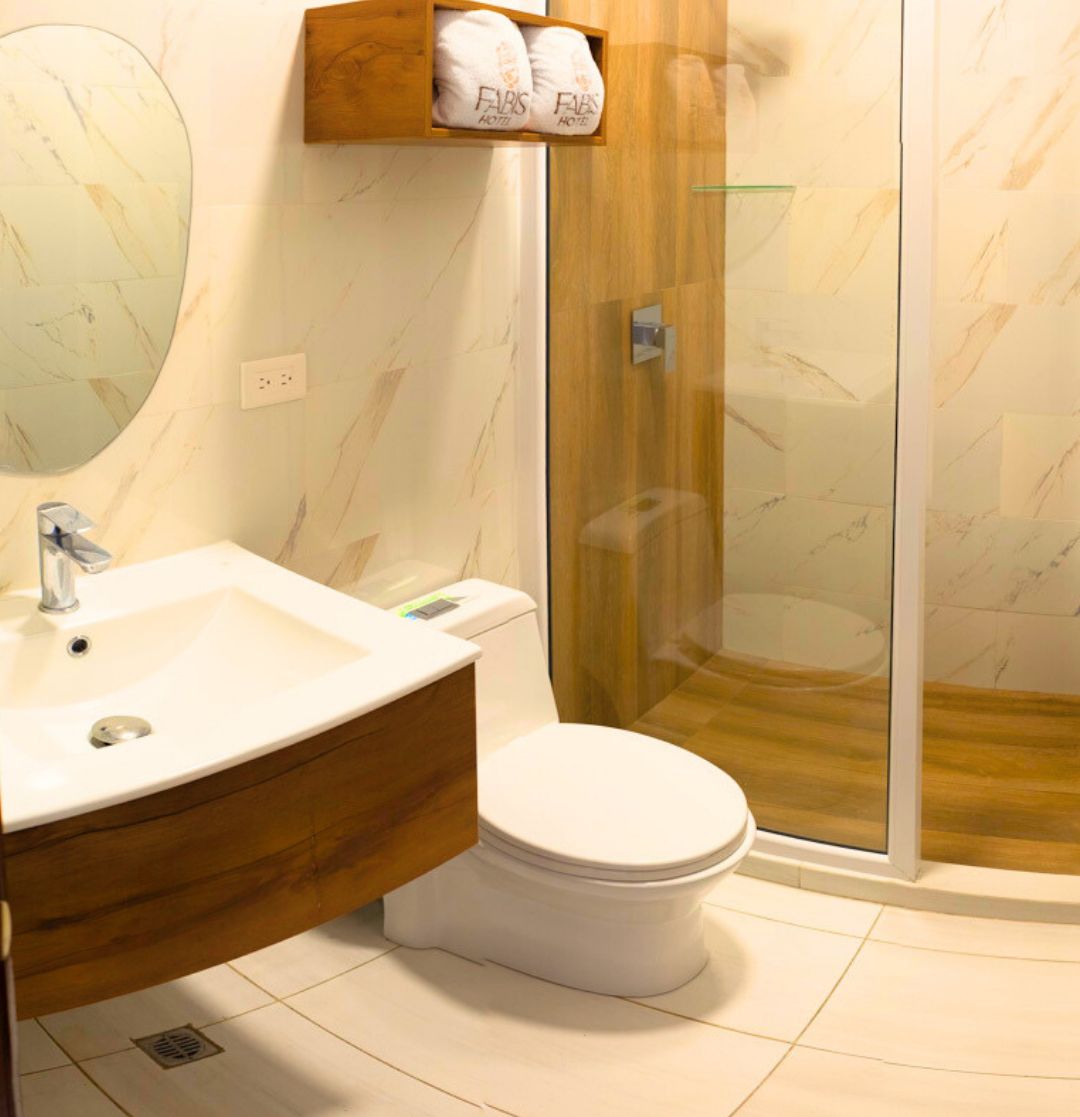 Ein modernes Badezimmer mit Marmorwaschbecken, Toilette und Duschkabine aus Glas.