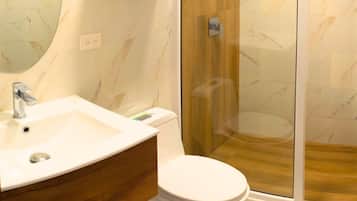 Ein modernes Badezimmer mit Marmorwaschbecken, Toilette und Duschkabine aus Glas.