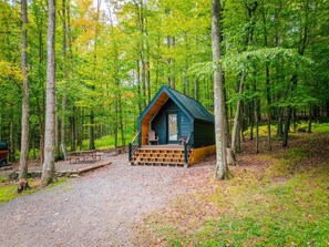 A cabin with a wooden deck and a single chair outside. - PA Grand Canyon Cozy Cabin (Wellsboro)