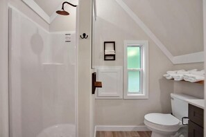 A bathroom with a shower, toilet, and a small window. - PA Grand Canyon Cozy Cabin (Wellsboro)