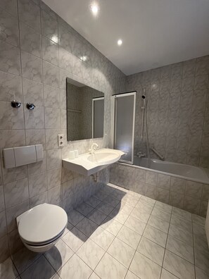 Un bagno moderno con toilette, lavabo, specchio e doccia.