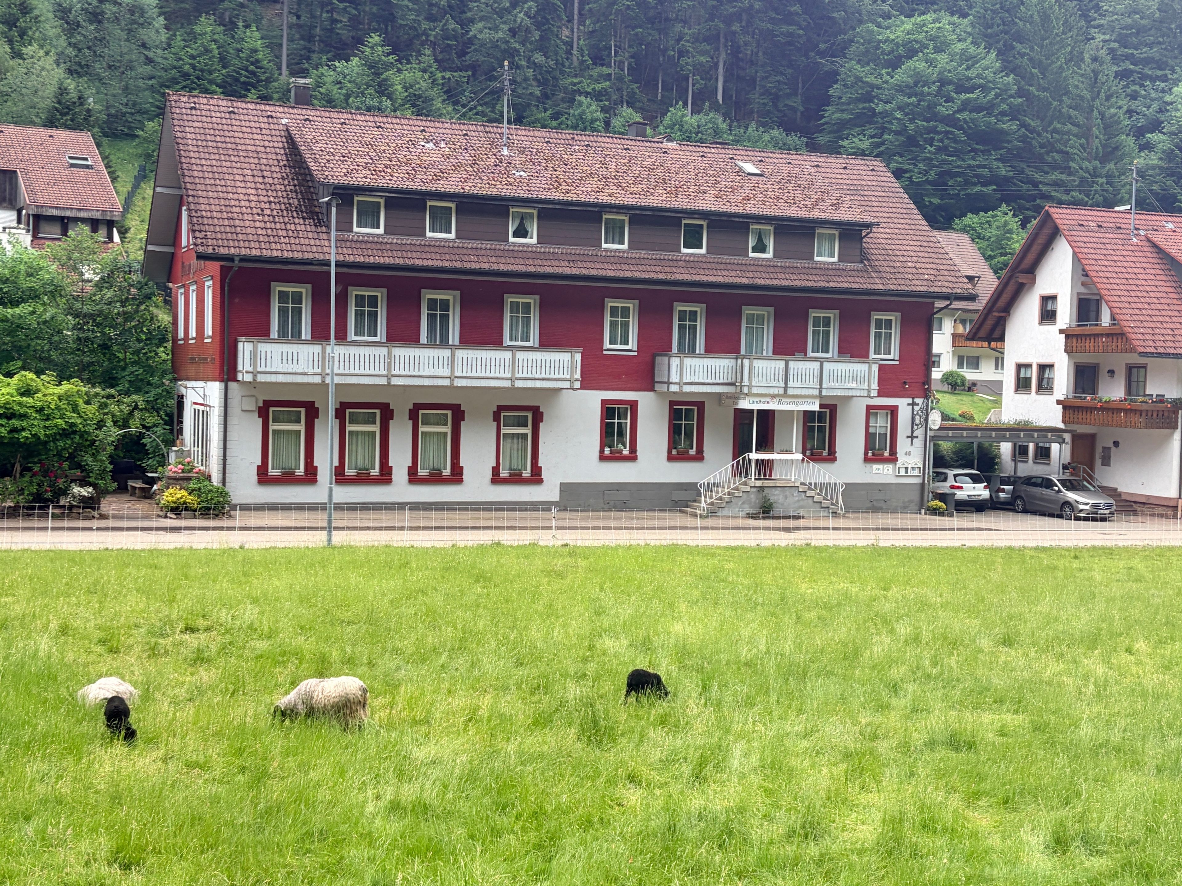 Un edificio a più piani con facciata rossa, balconi e un'area di parcheggio.