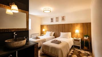 Hotellihuone, jossa on kaksi sänkyä, puinen pääty, suuri pyöreä pesuallas ja peili.