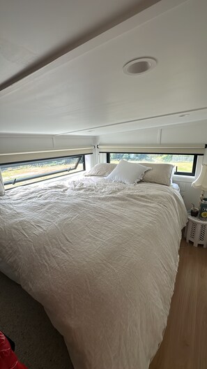 A bedroom with a large bed, a window, and a nightstand with a lamp.
