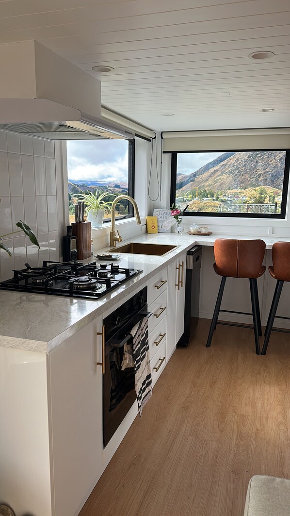 A modern kitchen with a large window, a gas stove, and a view of mountains.