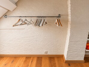 A room with a wooden floor, a white textured wall, and a metal clothes rack with various hangers. - Rue Isidoor Teirlinck 18 (Molenbeek-Saint-Jean)