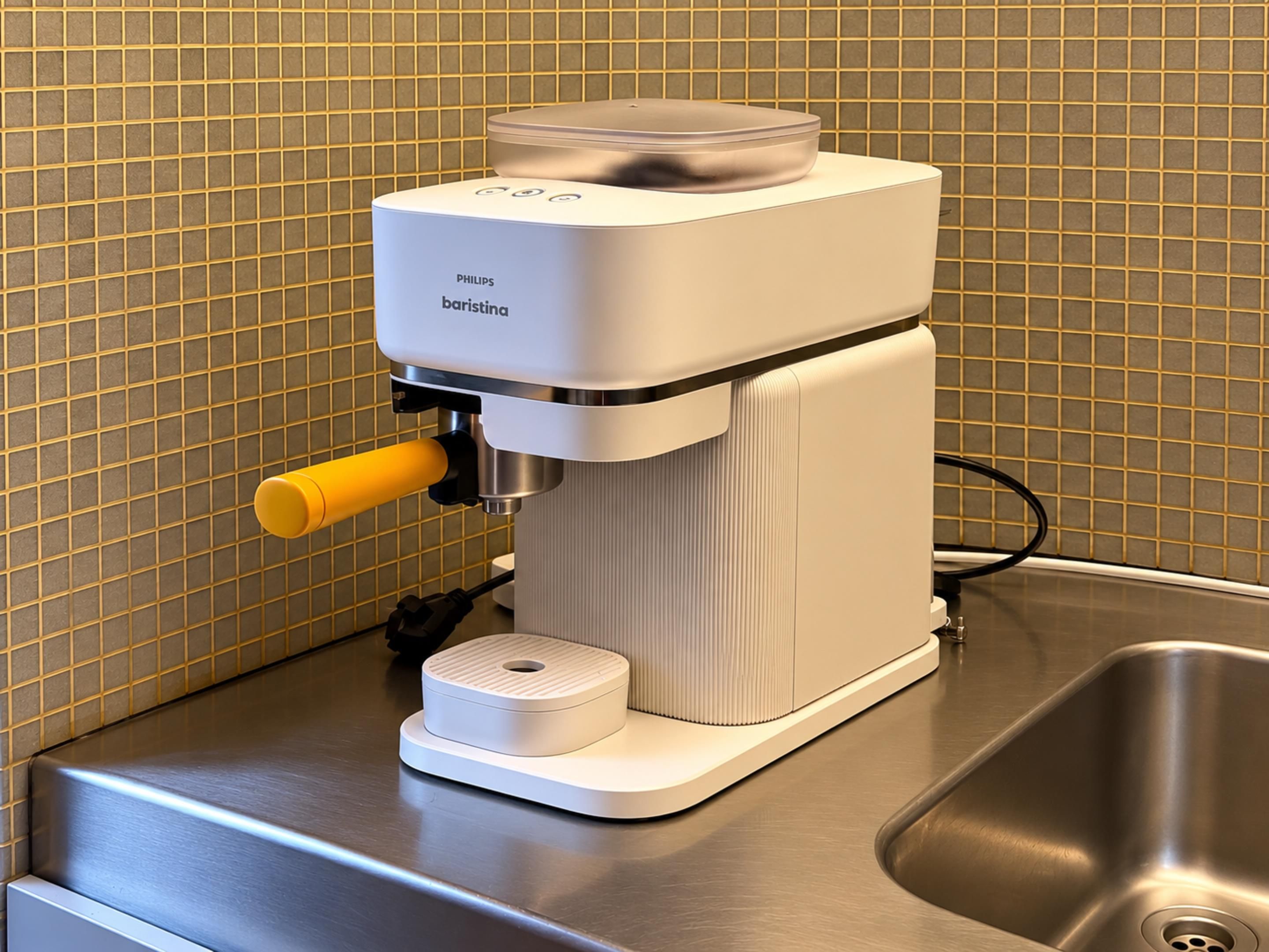 A barista coffee machine with a control panel, a yellow handle, and a power cord plugged in.