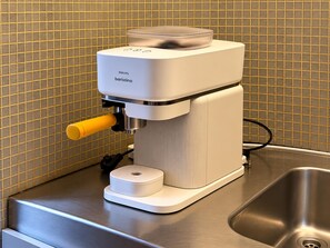 A barista coffee machine with a control panel, a yellow handle, and a power cord plugged in. - Rue Isidoor Teirlinck  (Molenbeek-Saint-Jean)