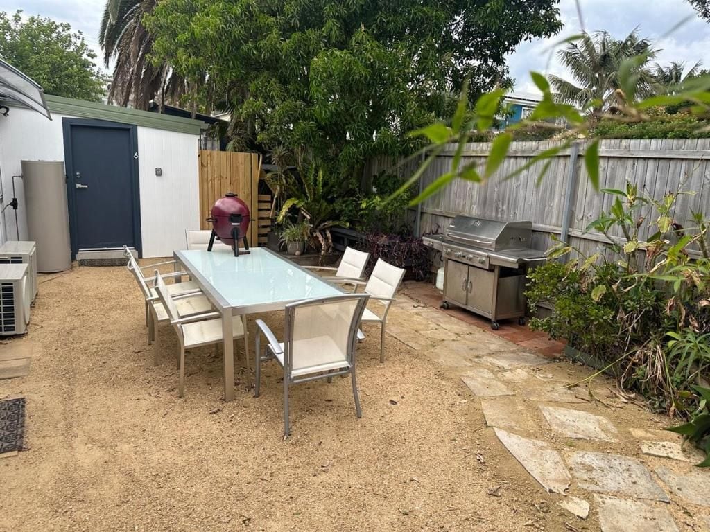 Un patio exterior con mesa y sillas, una parrilla y un cobertizo.