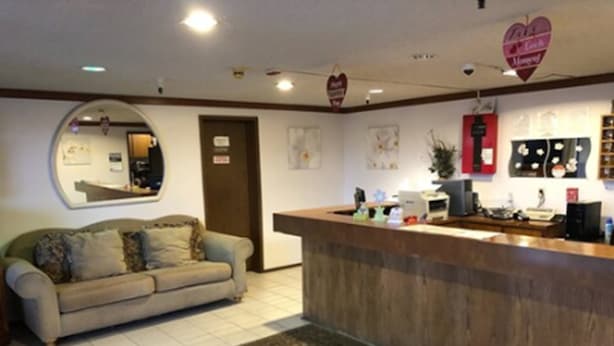 Un área de recepción con mostrador de madera, un sofá, un espejo y una decoración con forma de corazón en la pared.