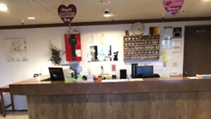 Una zona de recepción con mostrador de madera, una computadora y un reloj en la pared.