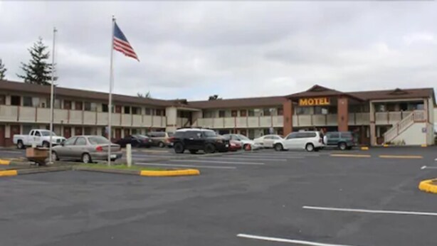 A motel with a parking lot, a flag, and a sign that reads "Motel".