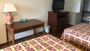 Una habitación de hotel con dos camas, un escritorio, un televisor y un aparador.