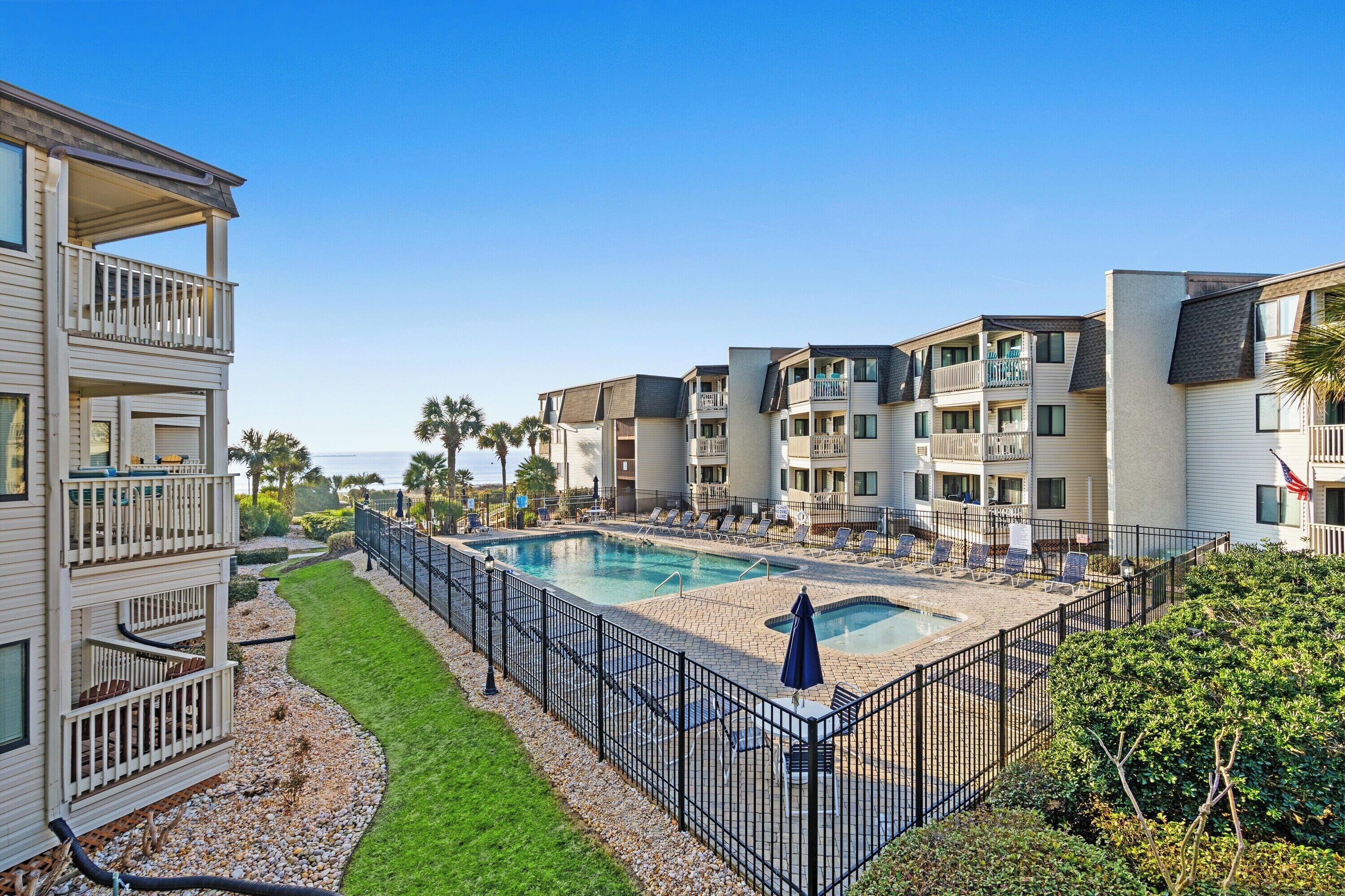 A multi-story residential building with balconies, a swimming pool, and a well-maintained lawn.