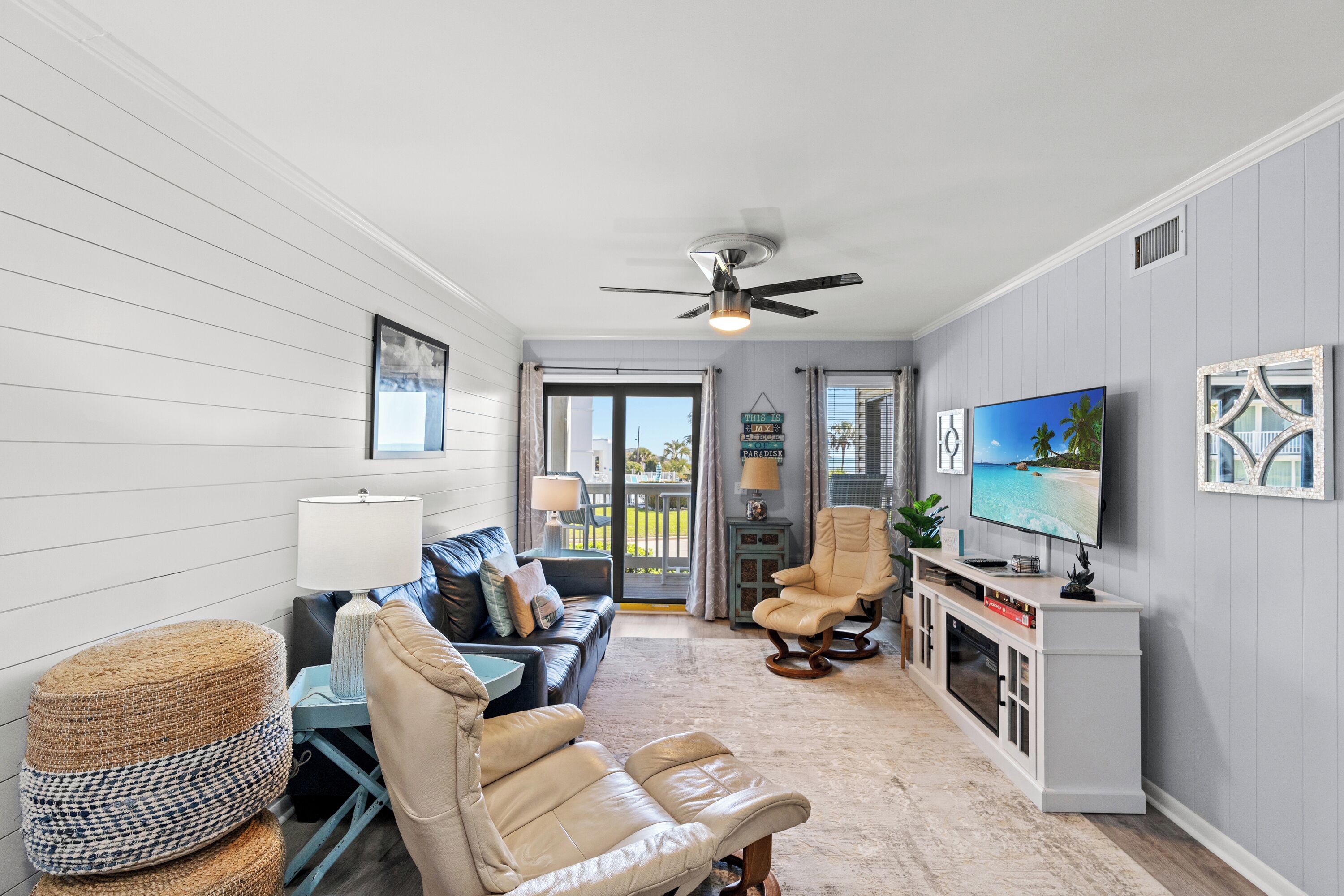 A spacious living room with a sofa, chairs, a TV, and a fireplace.