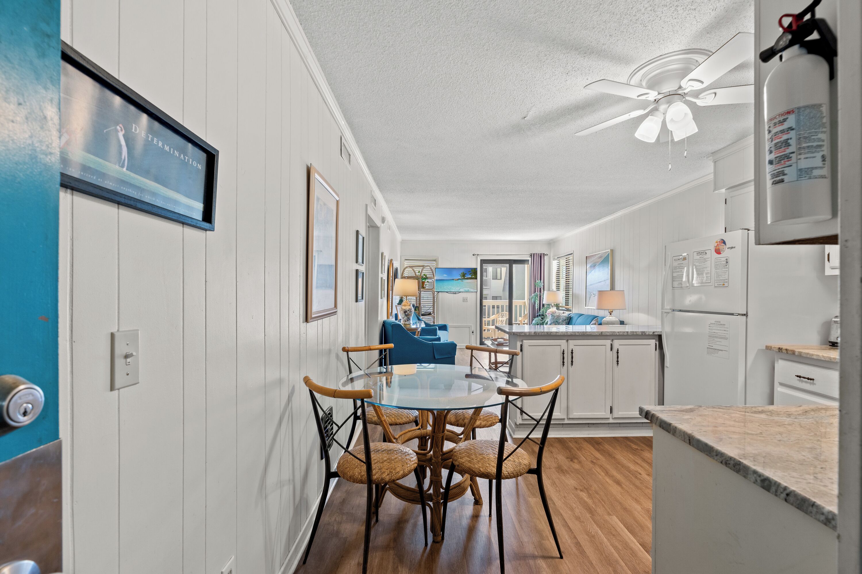A modern kitchen with white cabinets, a round glass table, and wicker chairs.