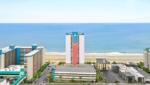 Hotel à beira-mar com uma torre imponente, estacionamento e vista para a praia.