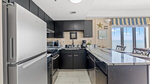 A modern kitchen with a built-in island, stainless steel appliances, and a view of the ocean. - The Palace Resort by Elliott Beach Rentals (Myrtle Beach)