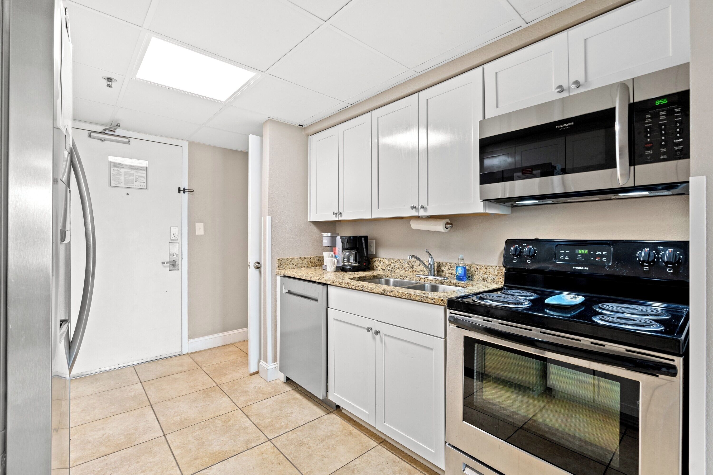 A kitchen with white cabinets, a stainless steel refrigerator, a microwave, a stove, and a dishwasher.