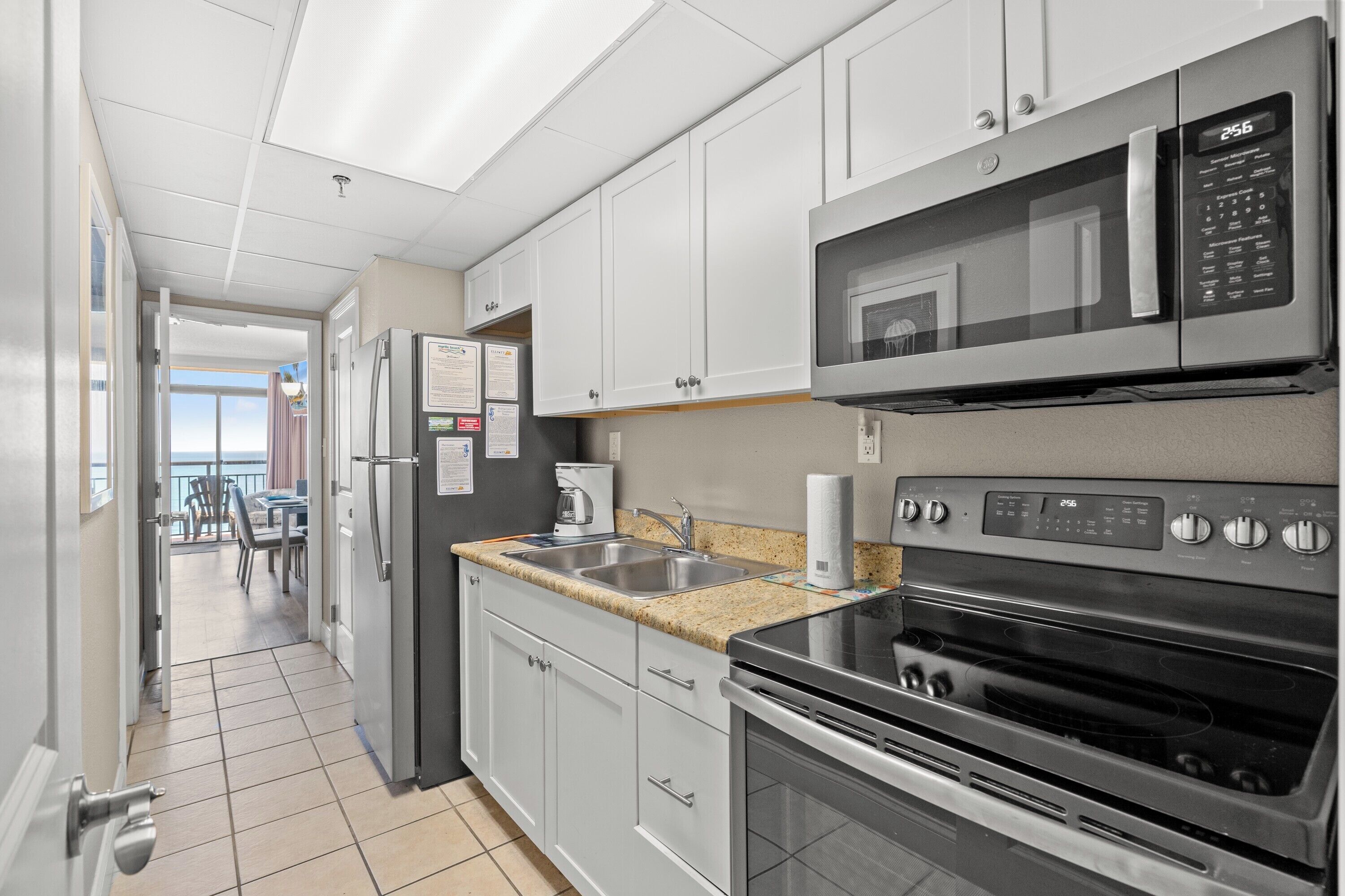 A kitchen with white cabinets, a microwave, a stove, and a refrigerator.