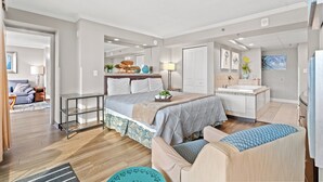 A modern bedroom with a bed, bedside table, and a bathroom with a bathtub. - Units at Caravelle Resort by Elliott Beach Rentals (Myrtle Beach)