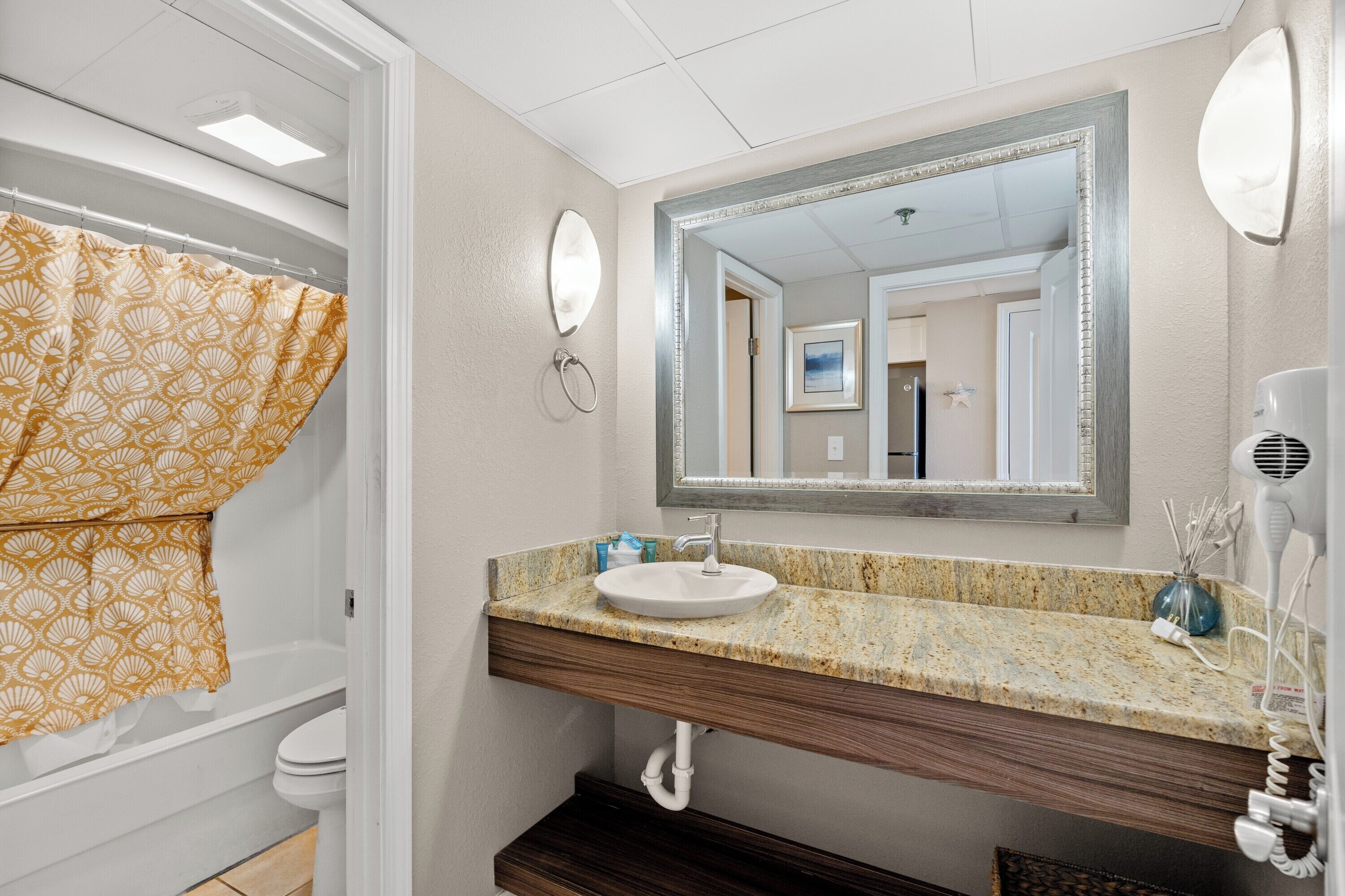 Une salle de bain équipée d’un lavabo, d’un miroir, d’un porte-serviettes et d’un rideau de douche.