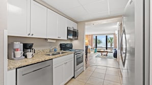 A modern kitchen with white cabinets, a stainless steel refrigerator, a microwave, and a coffee maker. - Units at Caravelle Resort by Elliott Beach Rentals (Myrtle Beach)