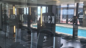 A gym with cardio equipment and a view of a swimming pool. - Sedona-Slate by Executive Apartments (Arlington)