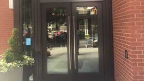 A building entrance with a glass door, the number 1510 above it, and a red brick wall to the right. - Sedona-Slate by Executive Apartments (Arlington)